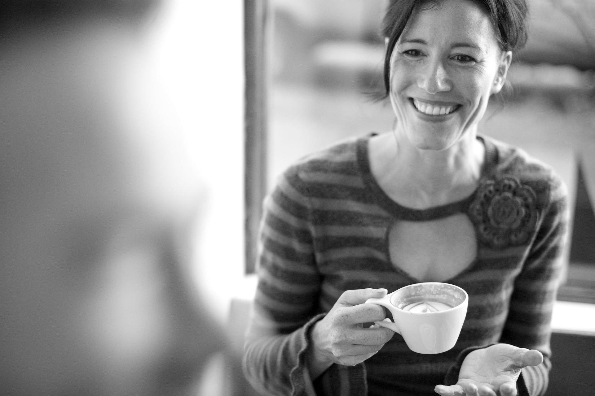 Foto en blanco y negro de una mujer con una taza sonriendo
